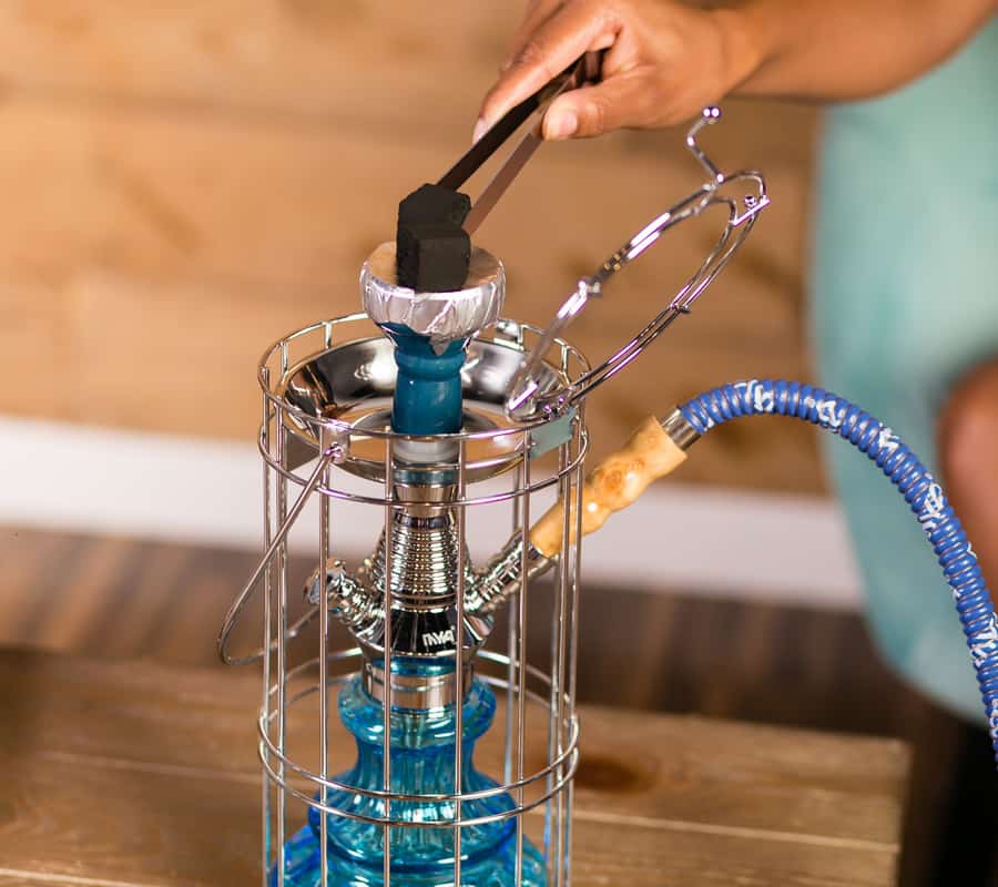 Charcoal on top of hookah with tongs