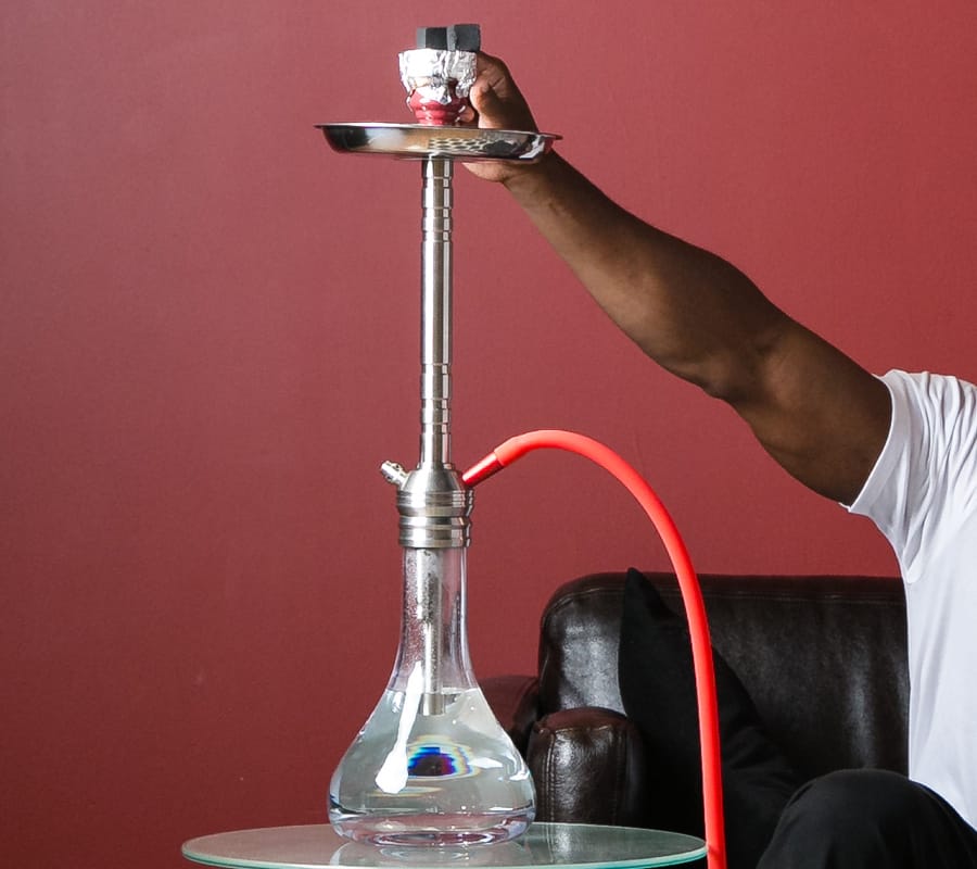 Male putting charcoal on top of hookah